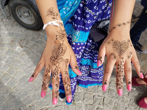 Hands displaying intricate mehndi designs and pink-painted nails.