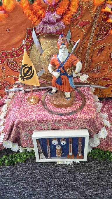A decorative altar with a statue of a warrior, adorned with a flag and musical instruments.